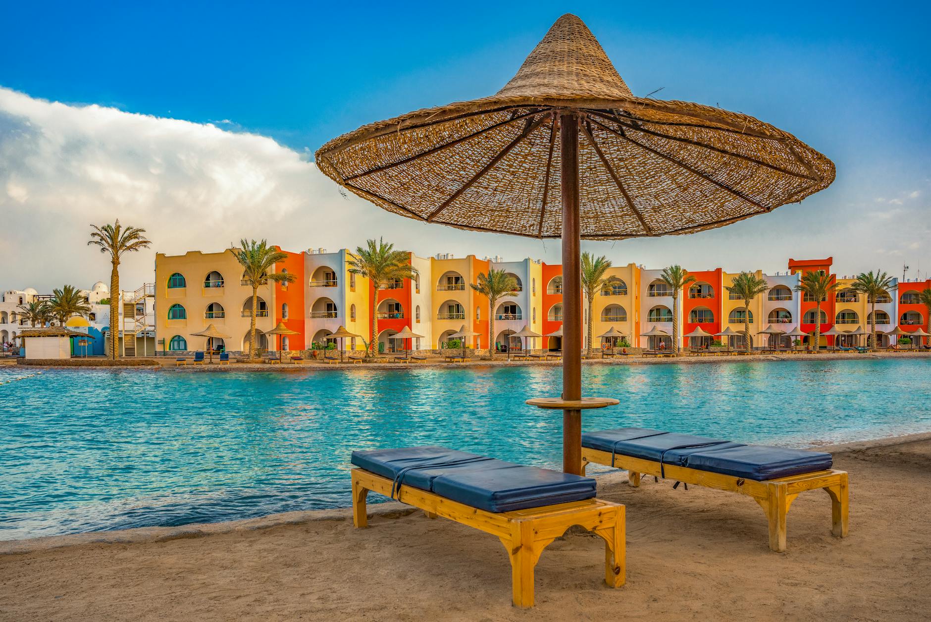Relax by the vibrant poolside at a stunning summer resort, featuring sunbeds and scenic views.