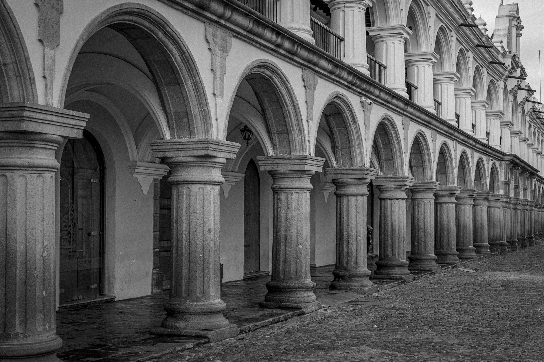 Black and white photo capturing the elegant arches of Palacio de los Capitanes, a landmark in Antigua Guatemala.