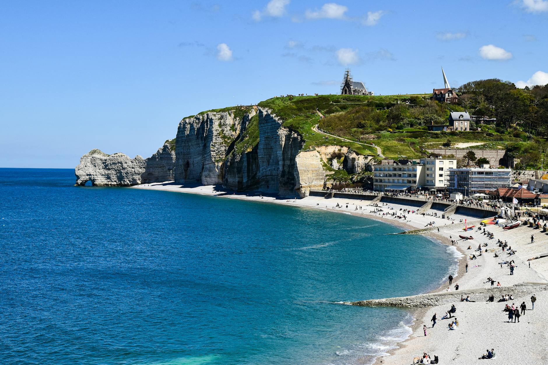 Beautiful coastal view of the famous cliffs and beach at Étretat, perfect for summer tourism.