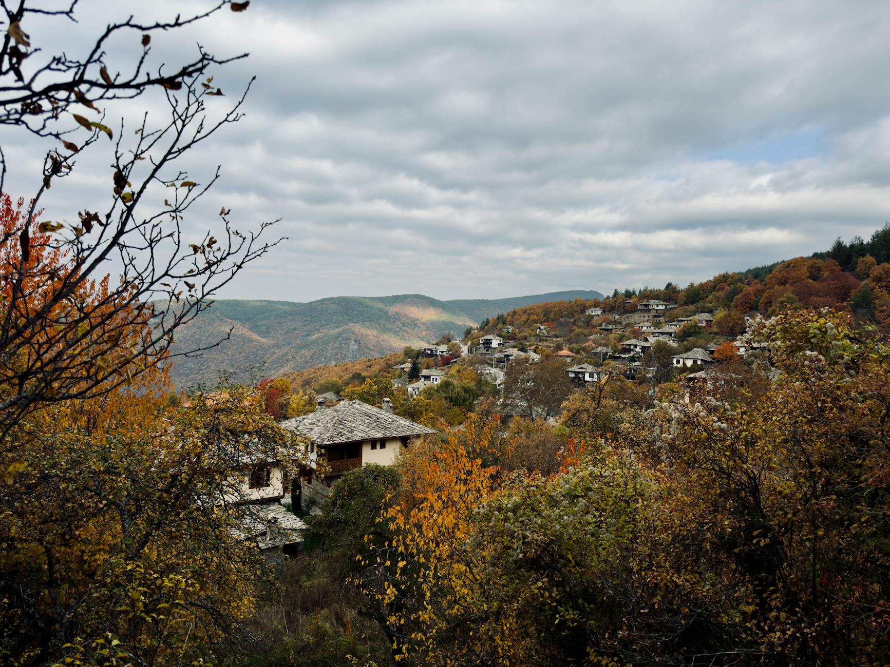 Picturesque autumn view of a traditional village in the Bulgarian mountains, surrounded by vibrant foliage.