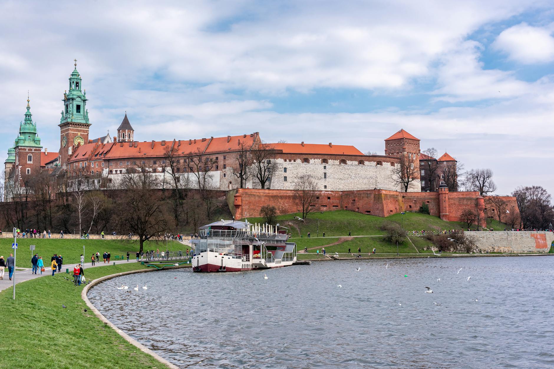 Scenic view of Wawel Castle with boats on the Vistula River, Kraków, Poland.