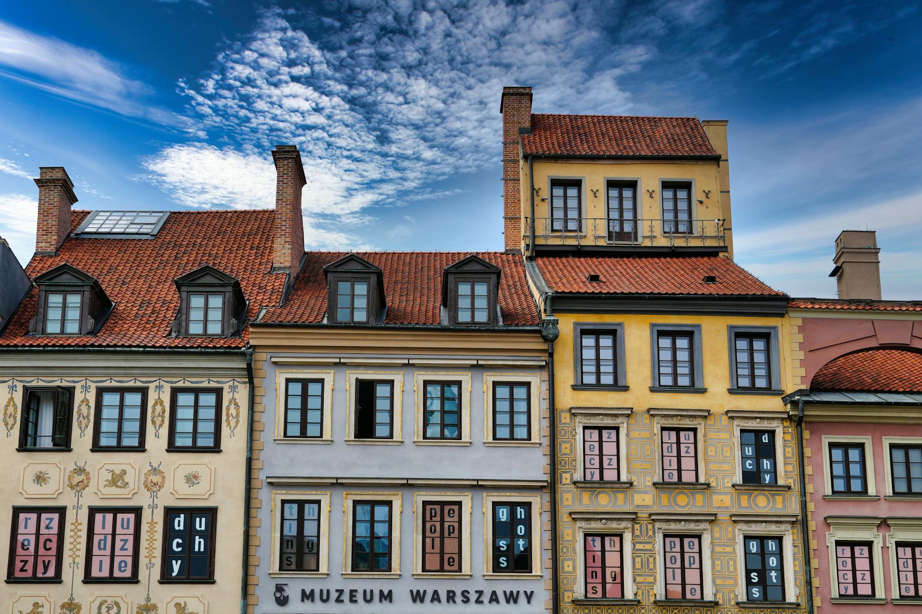 Colorful facades of historic buildings in Warsaw, Poland, under a vibrant blue sky.