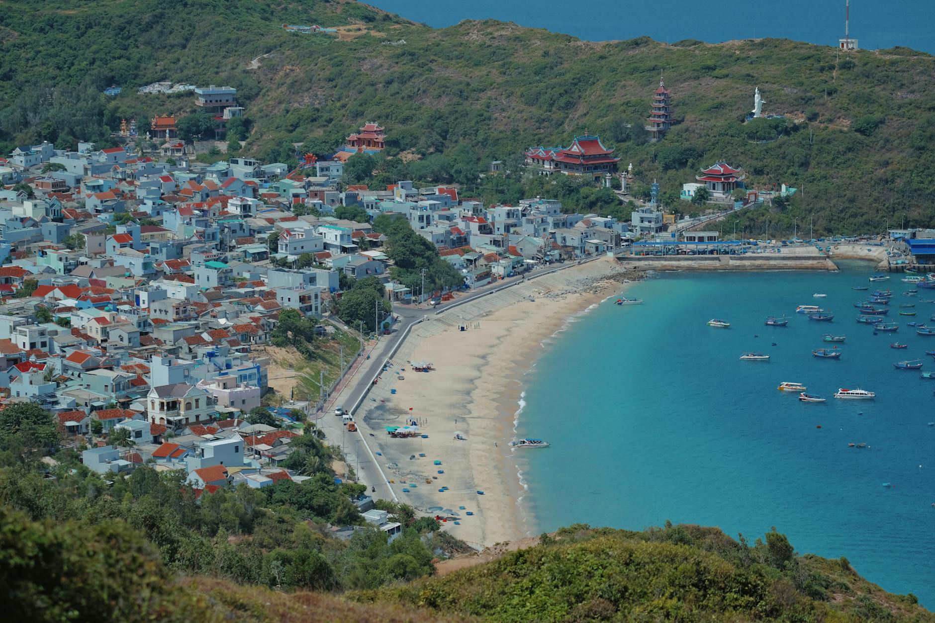 Stunning aerial view of a beachside town surrounded by hills and vibrant blue waters.