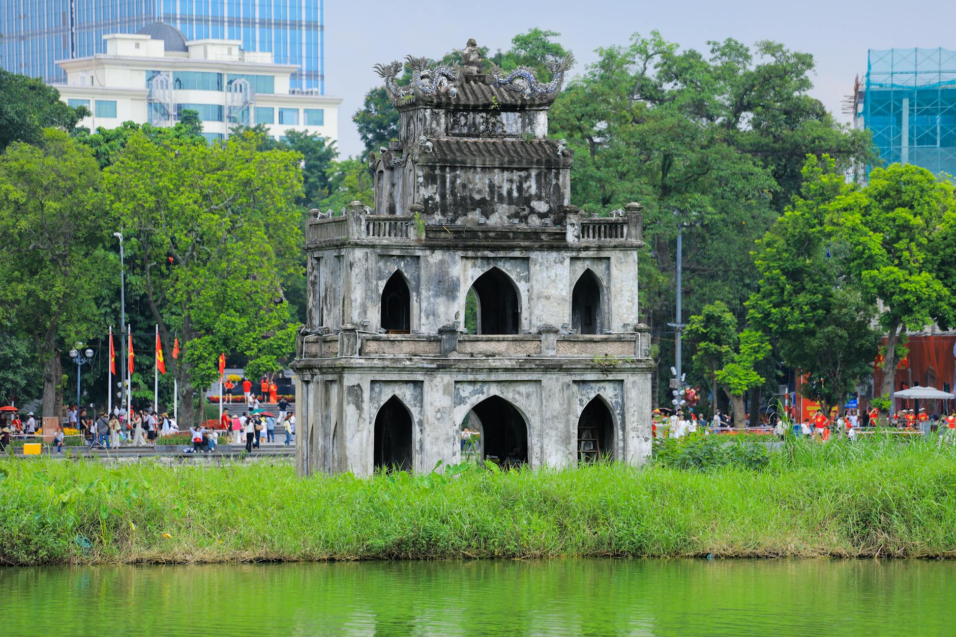 Historic Turtle Tower in Hoan Kiem Lake surrounded by lush greenery in Hanoi, Vietnam.