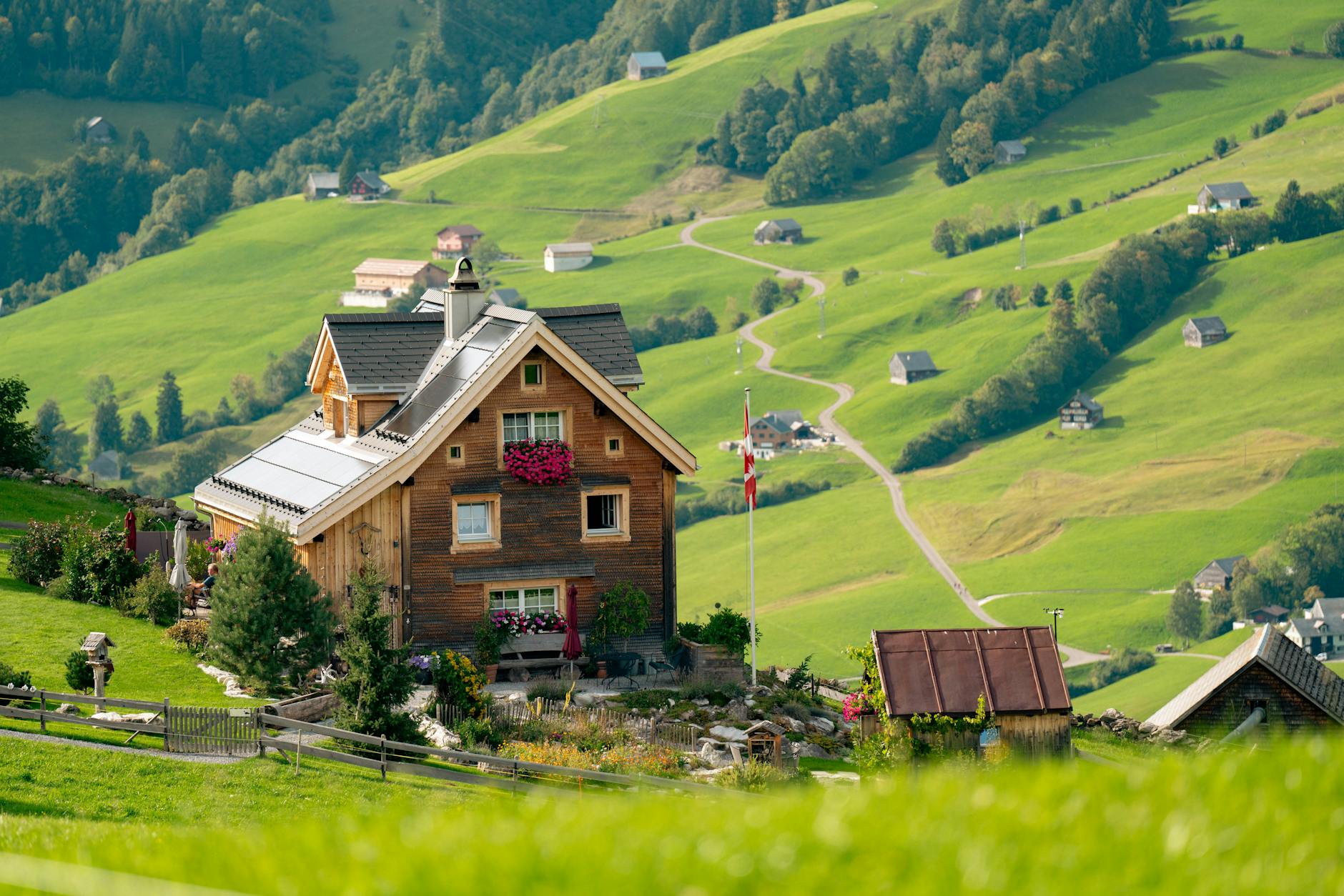 Idyllic Swiss chalet surrounded by green rolling hills and scenic mountain views, perfect for travel inspiration.