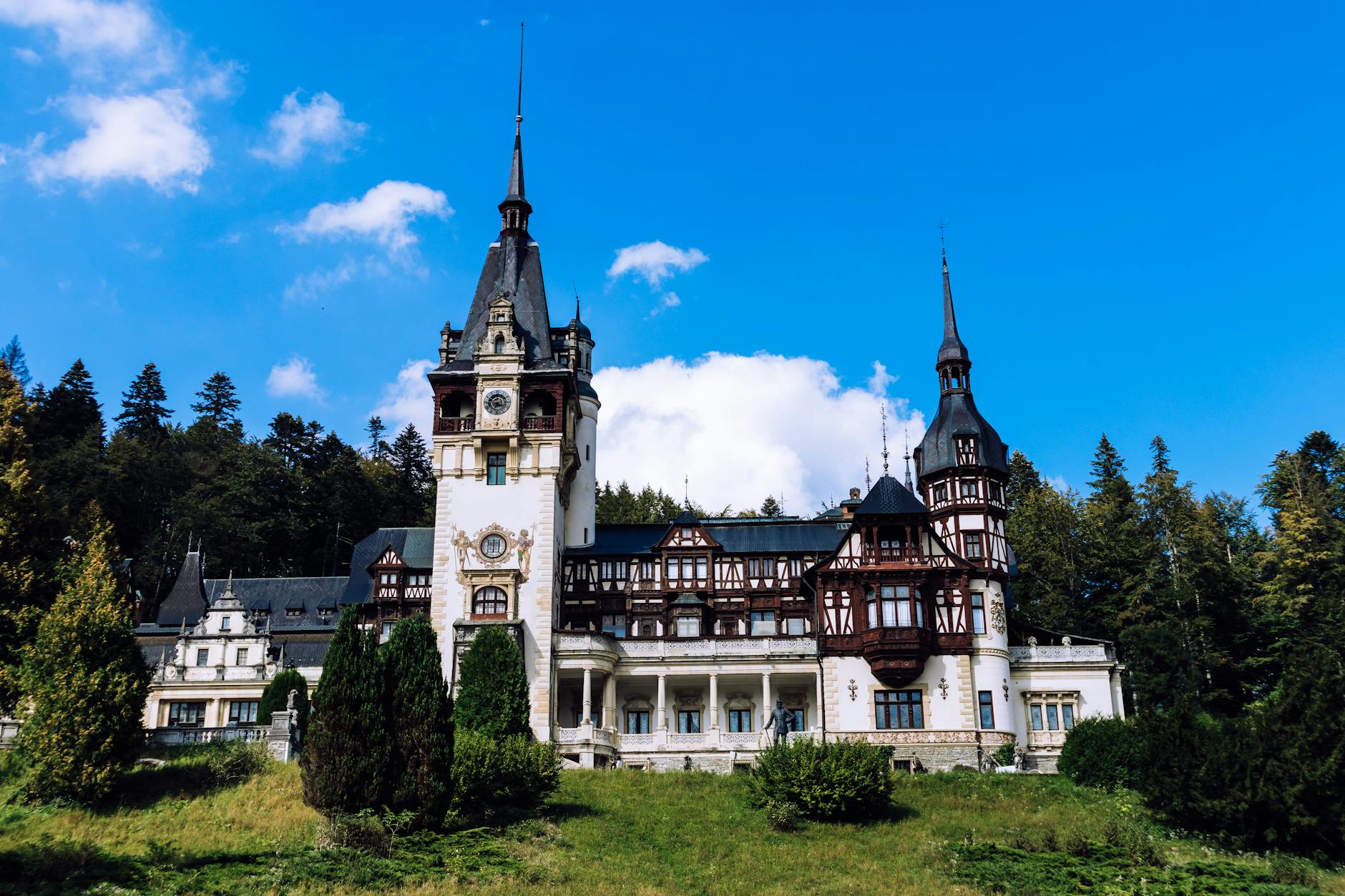 Stunning view of Peles Castle, a Neo-Renaissance landmark in Romania, under a bright blue sky.