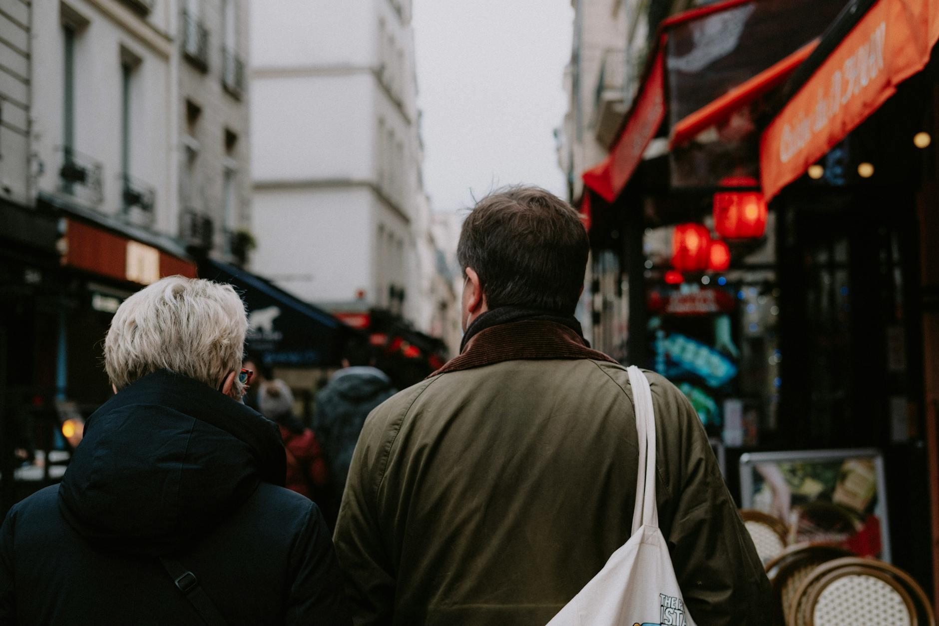 Two adults exploring bustling downtown streets, surrounded by shops and cafes.