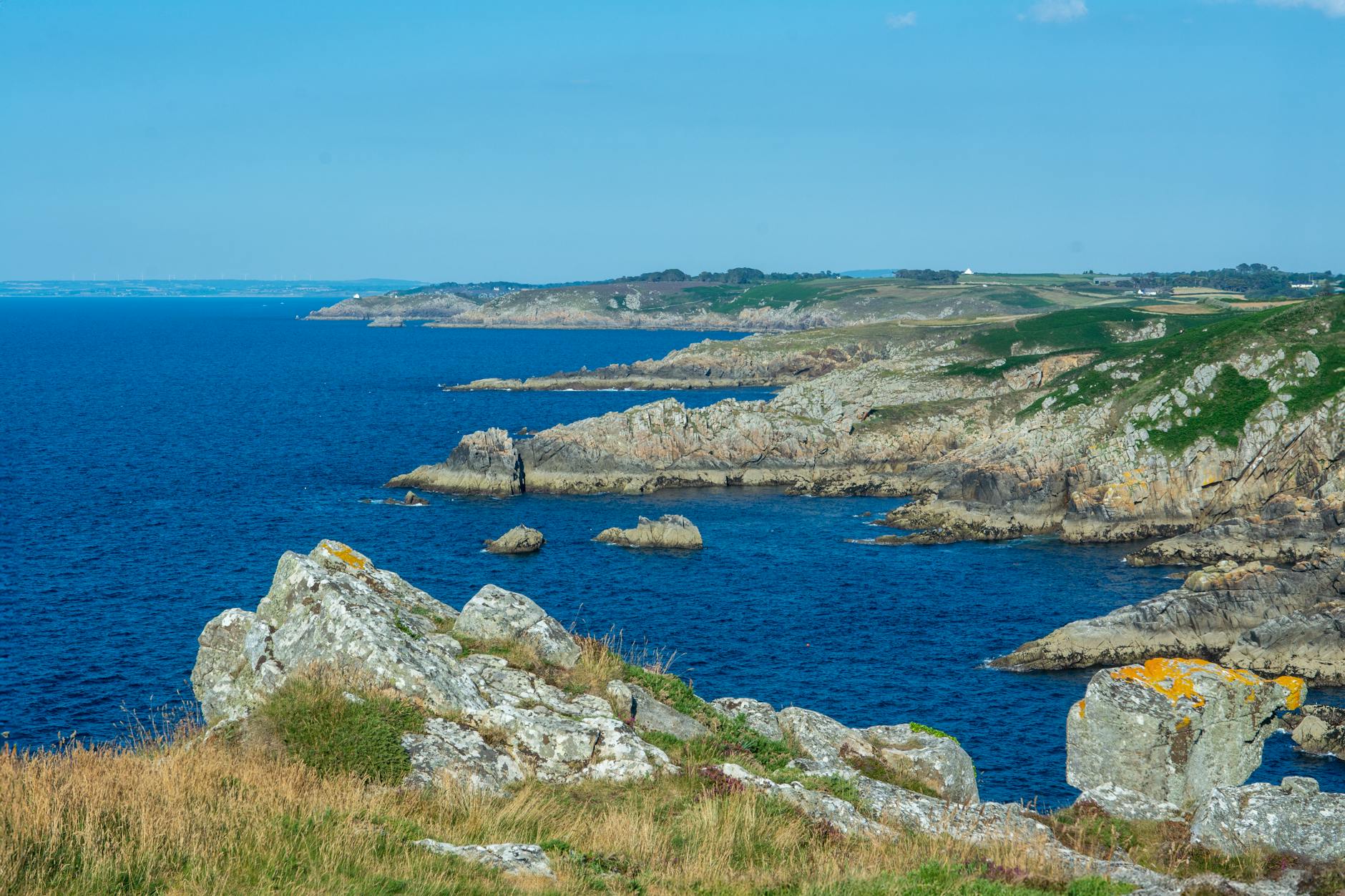 Picturesque rocky coastline of Pointe de Beuzec, France showcasing clear blue waters and rugged cliffs.