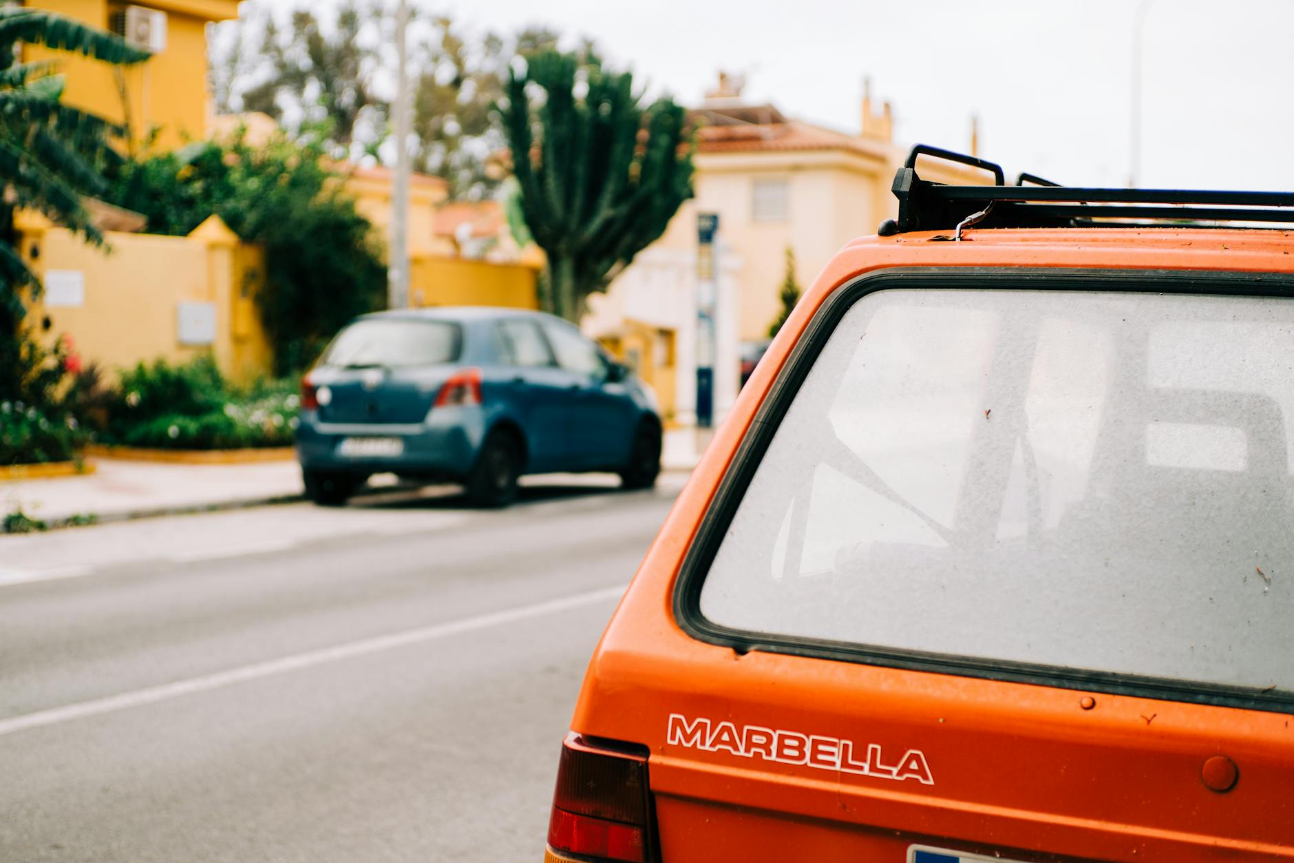 Vintage car with visible trunk lid on a sunny street in Málaga, Spain.