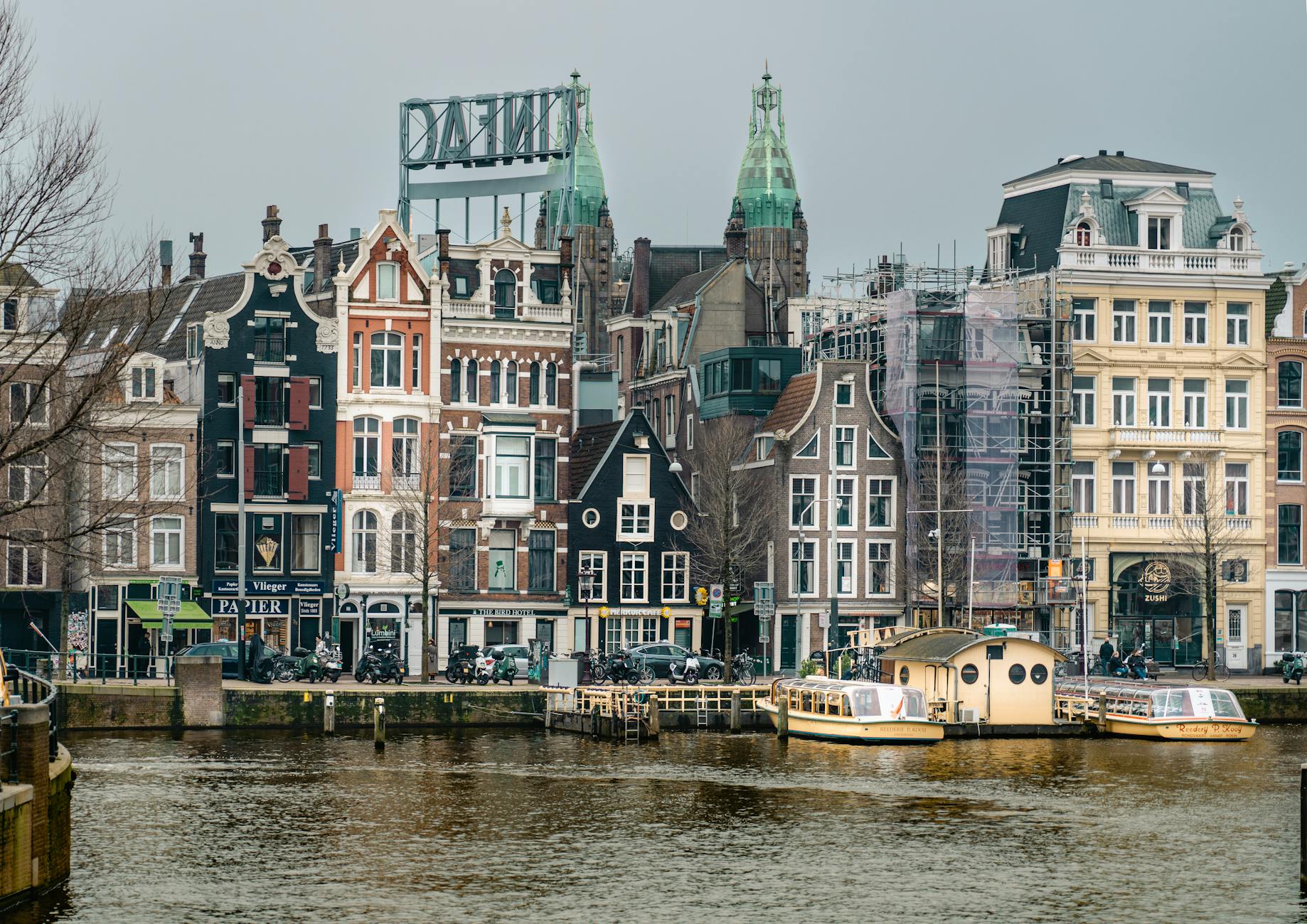Traditional canal houses in Amsterdam captured on a serene winter day, showcasing Dutch architecture.