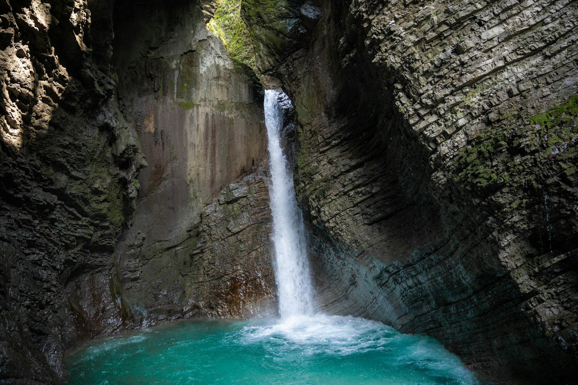 Stunning waterfall cascading in a secluded rocky gorge with turquoise water.