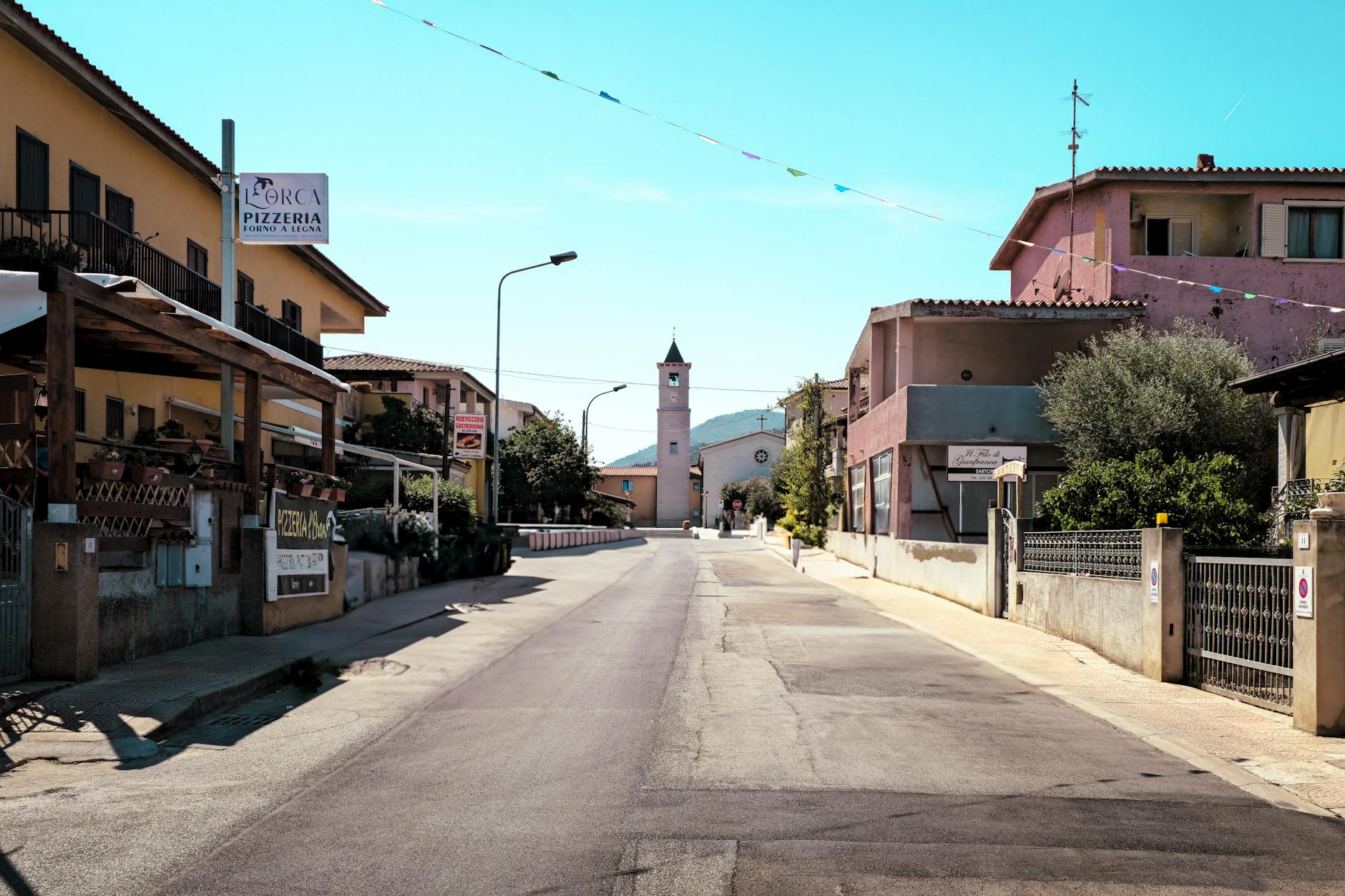 Sunny street scene in Porto San Giorgio, showcasing local architecture and a distant clock tower.