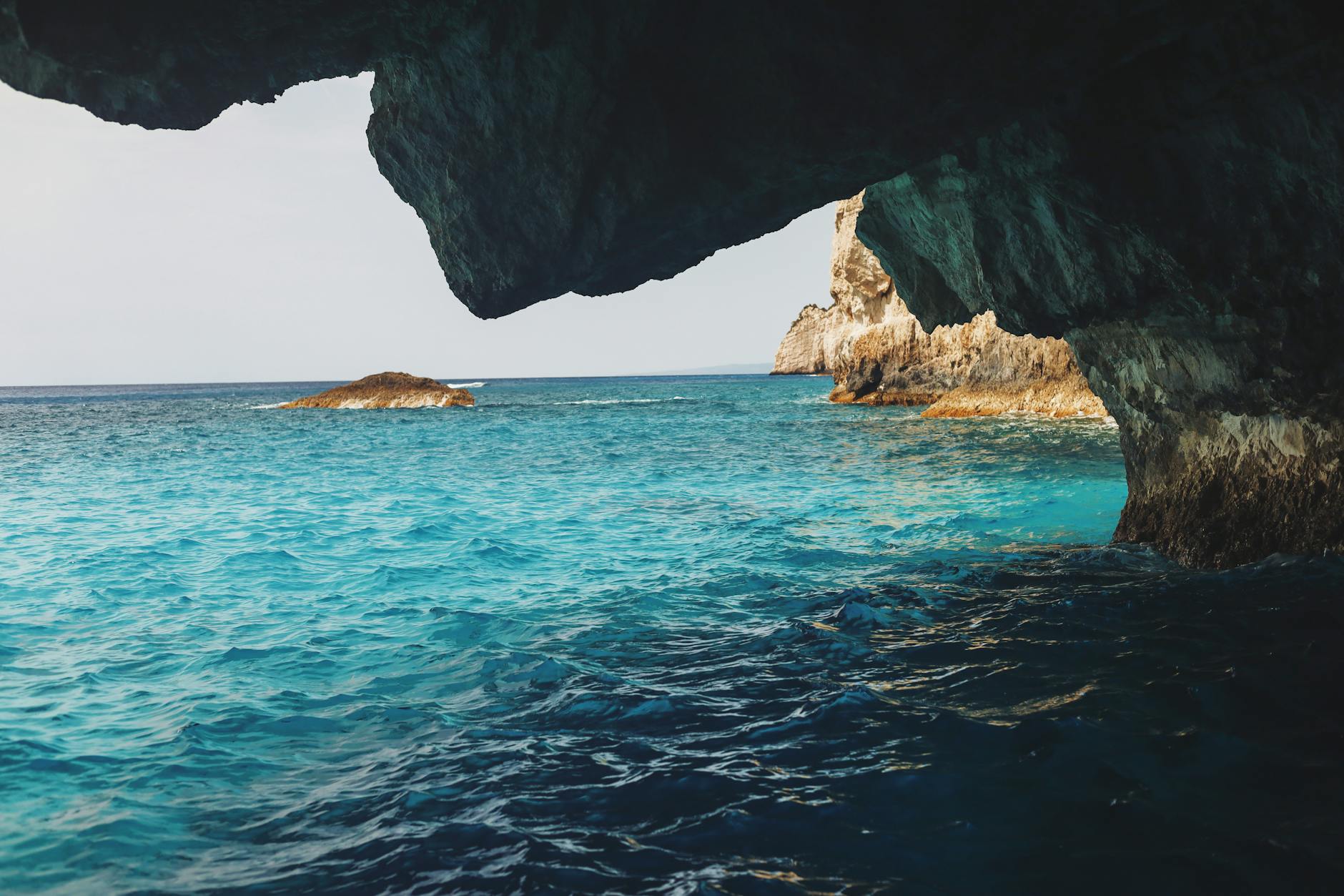 Experience the beauty of a coastal cave framing sparkling blue waters, perfect for travel and nature enthusiasts.