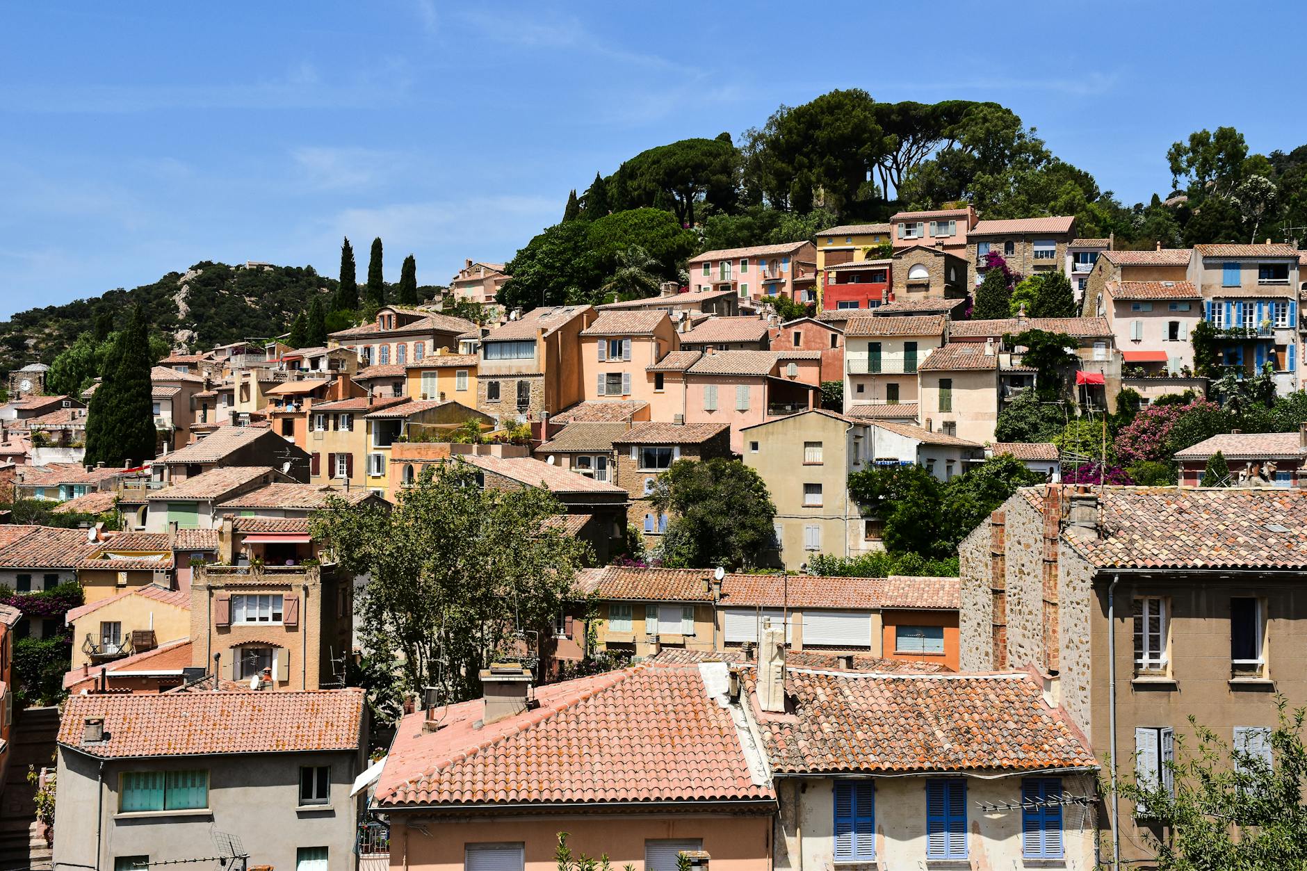 Charming hillside view of colorful houses in Bormes-les-Mimosas, France, under a clear blue sky.