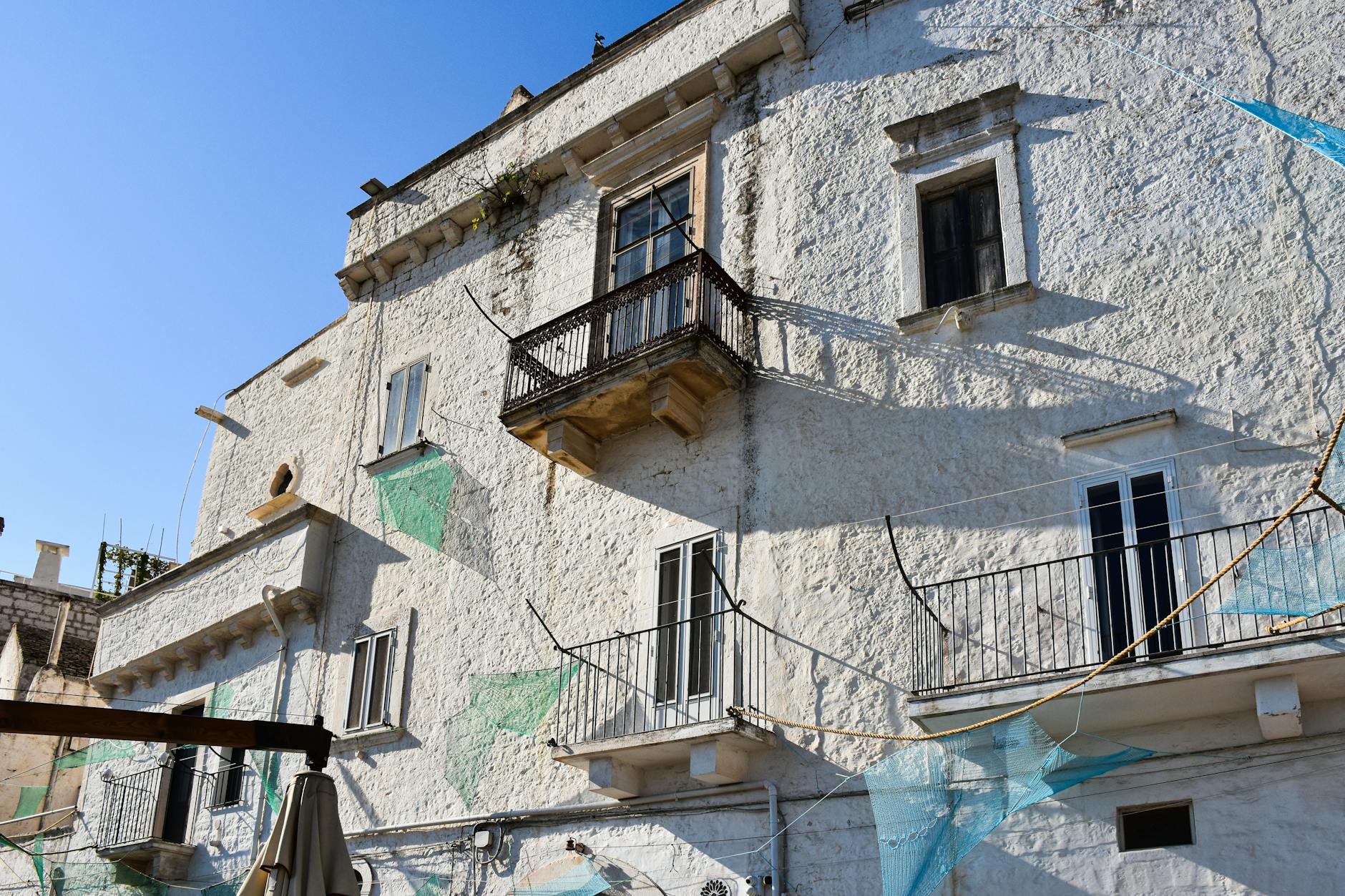 Historic white stone building in a sunny southern Italian town, showcasing architectural charm.