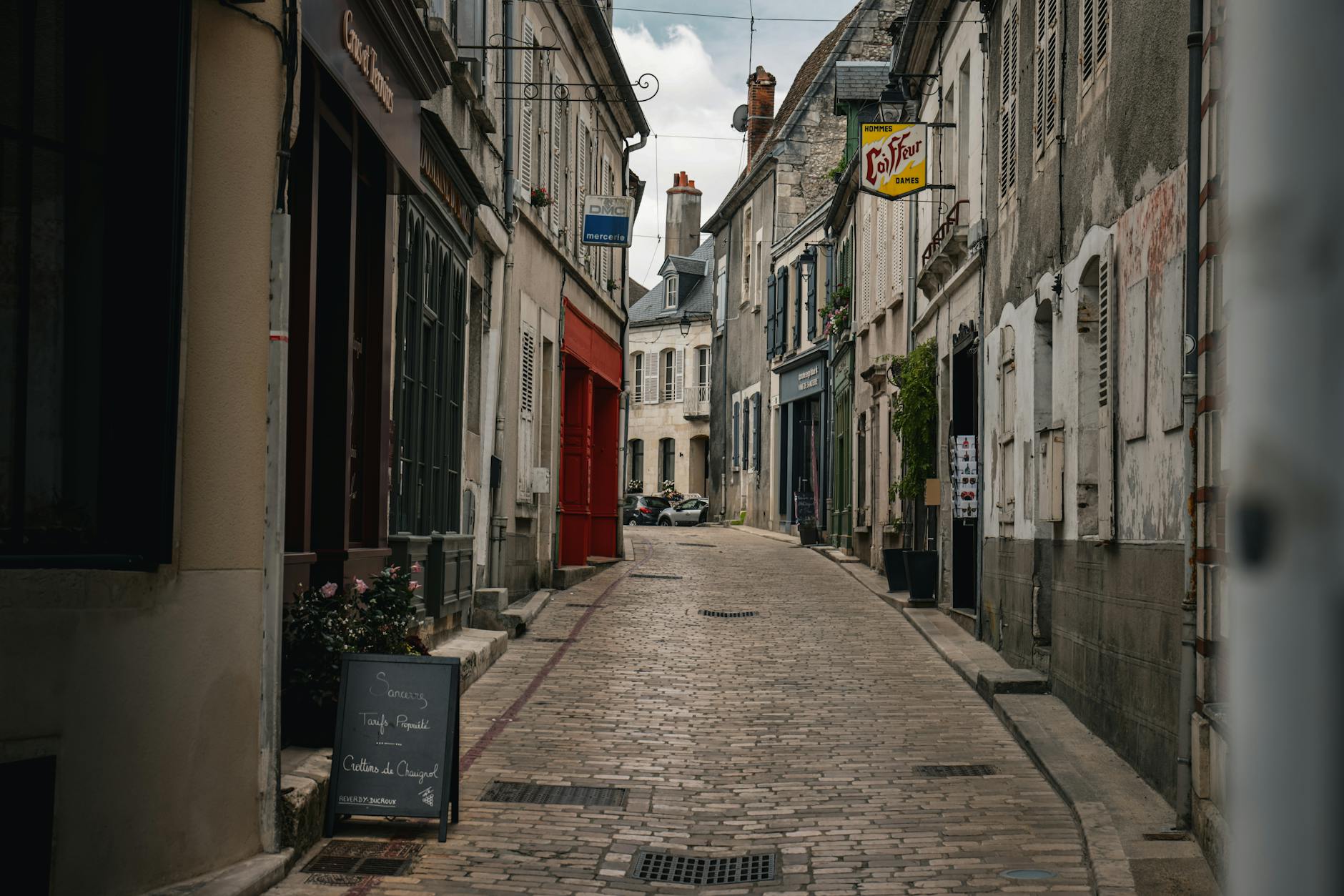 Explore a picturesque cobblestone street in Sancerre, France, showcasing historic architecture and cozy cafes.