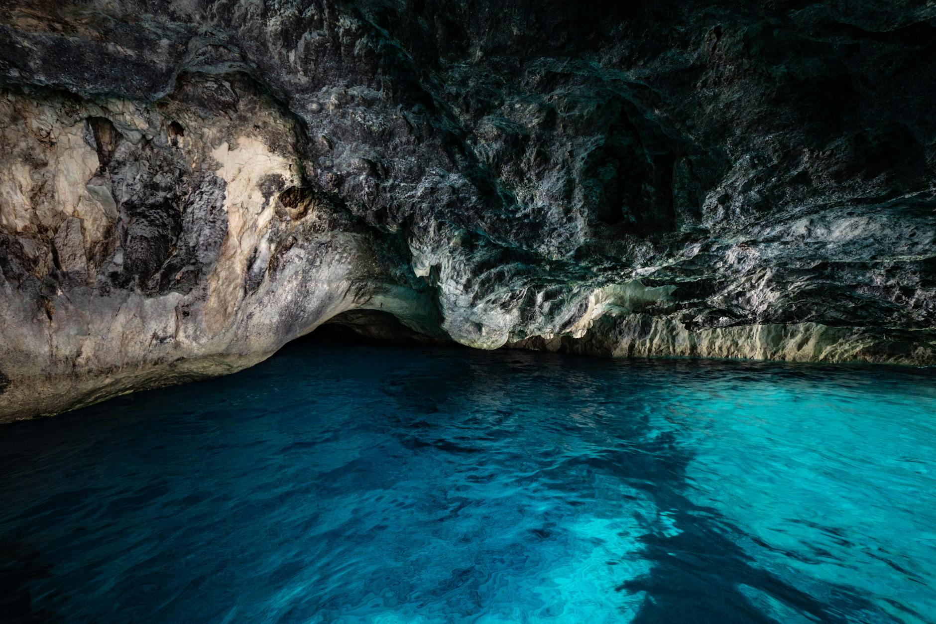 Discover the breathtaking beauty of an underground cave with clear blue waters and rugged rock formations.