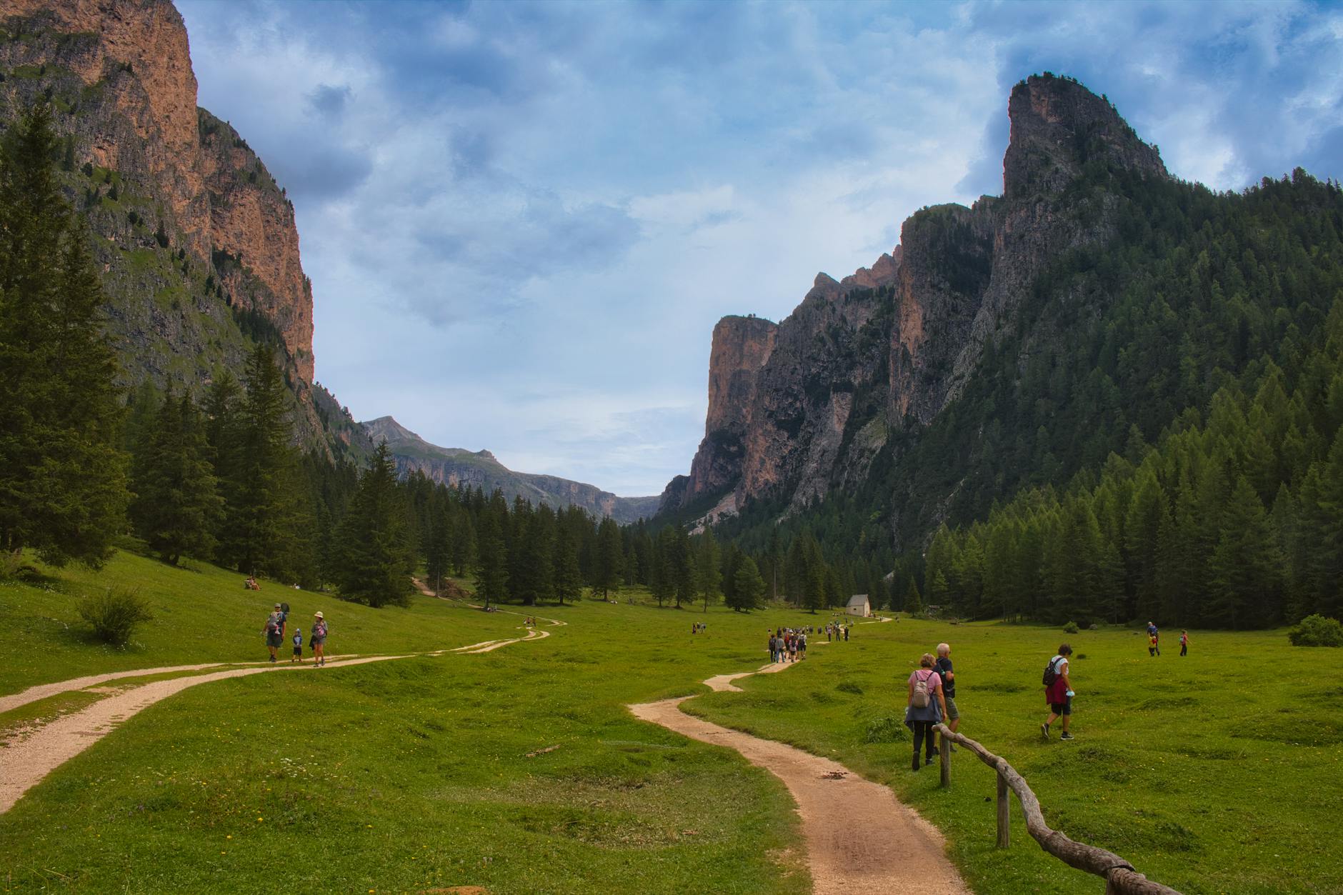 A picturesque hiking trail through the Dolomites in Selva di Val Gardena, Italy, surrounded by lush greenery and towering cliffs.