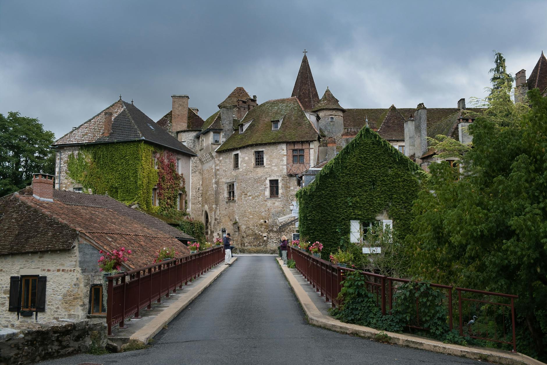 A picturesque view of a French château with ivy-covered walls and a serene walkway.