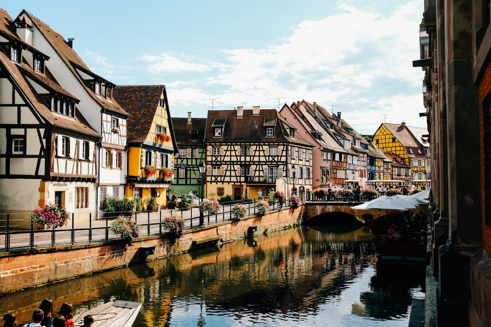 Exterior of old traditional half timbered houses located on embankment near canal flowing in Colmar on sunny day