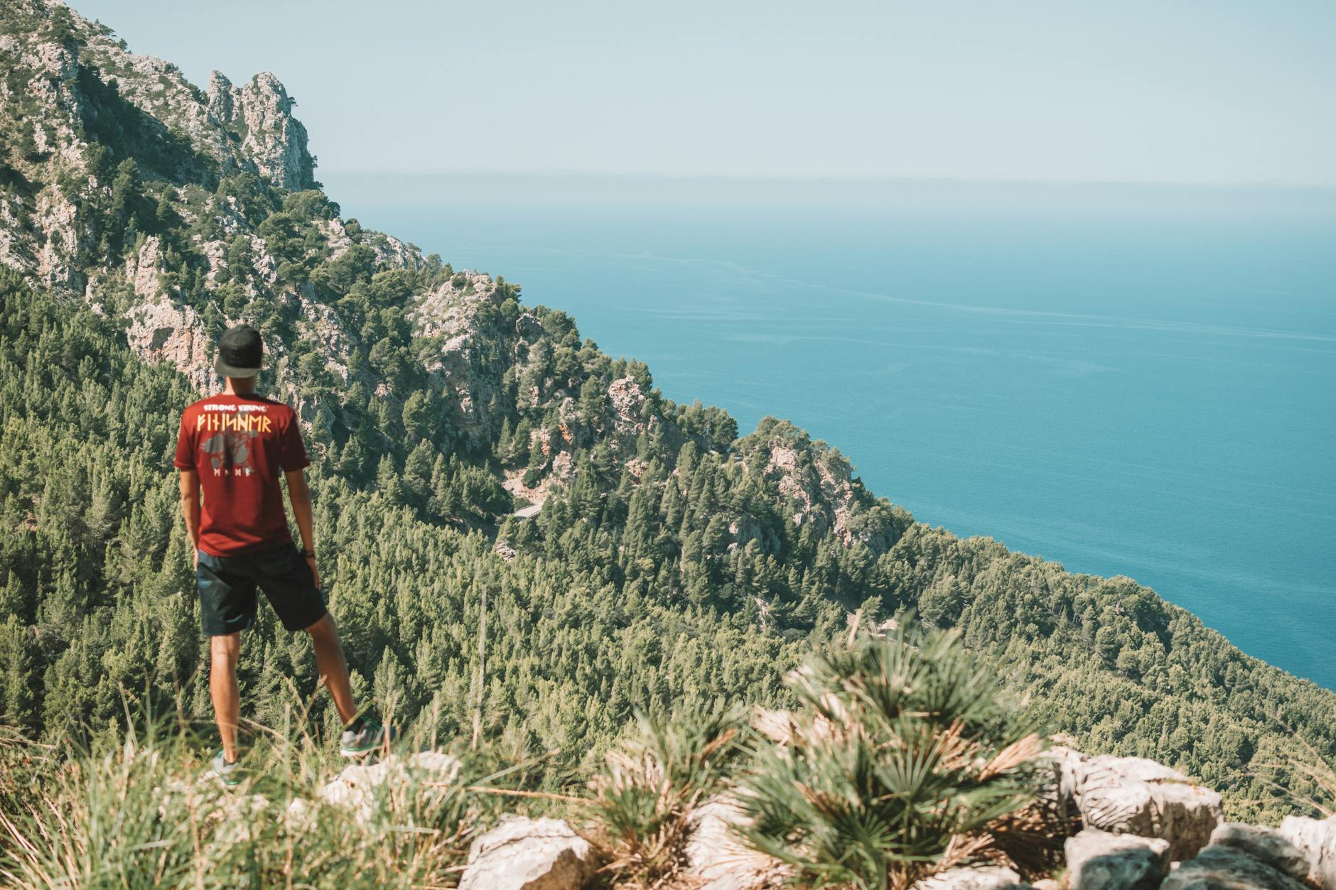 A man enjoying the breathtaking coastal view from the mountains in Mallorca, Spain.