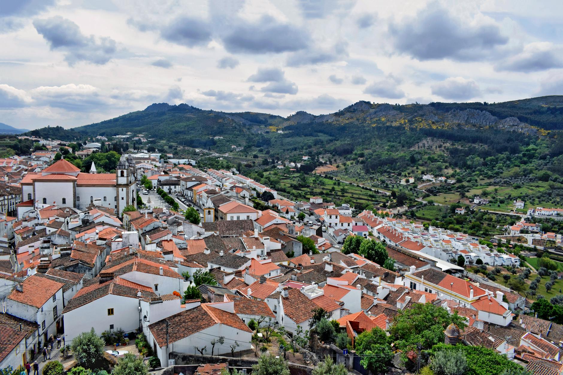 Aerial view of Marvão's charming white houses and red roofs against a mountainous backdrop in Portugal.