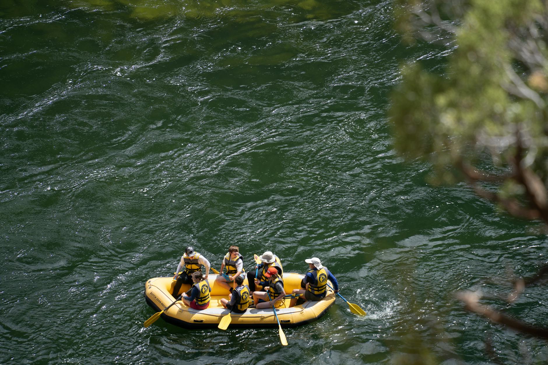 A group of people rafting on Green River in a yellow boat, enjoying the adventure in Utah.