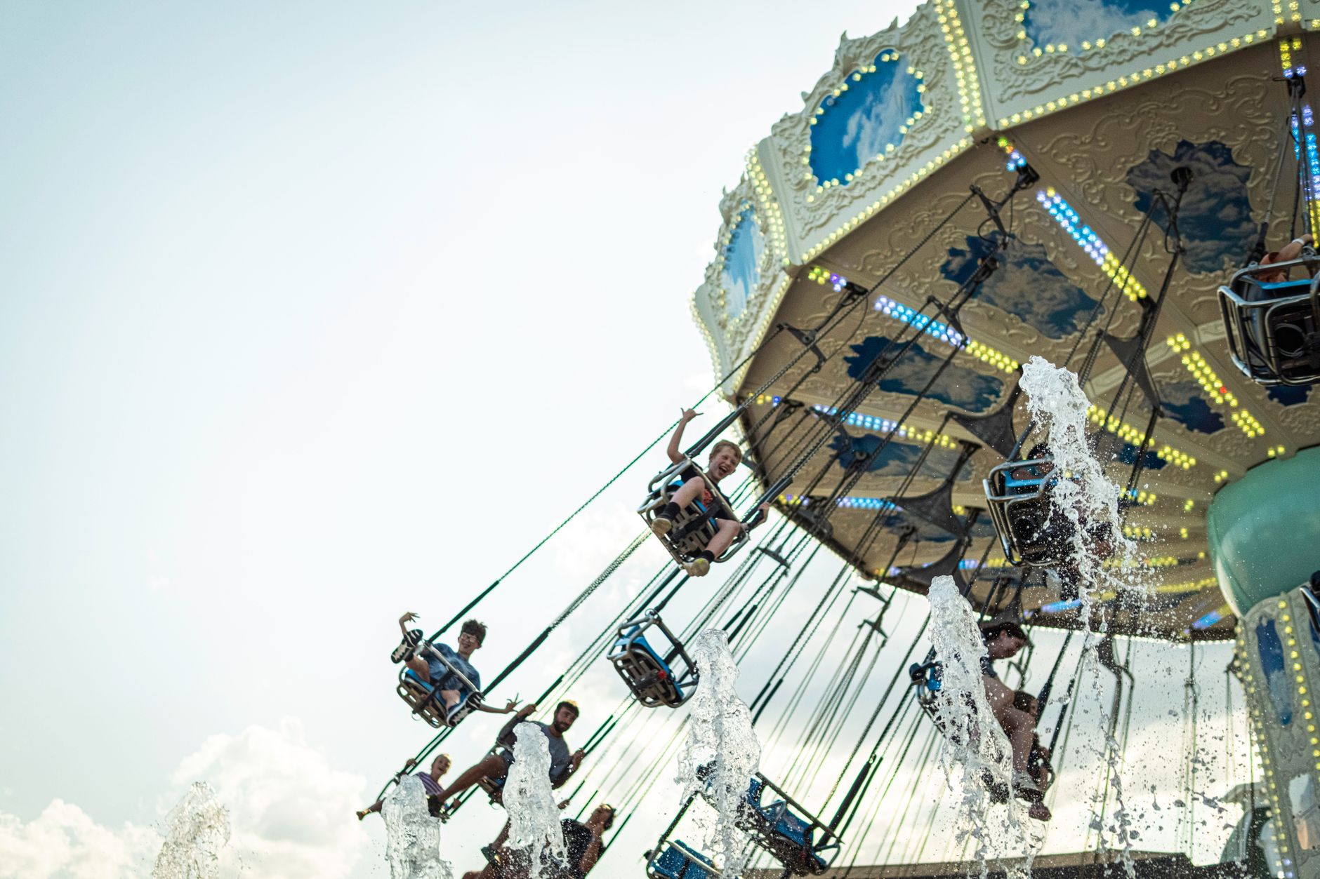 Exciting aerial swing ride at theme park, perfect for thrill-seekers captured in action on a sunny day.