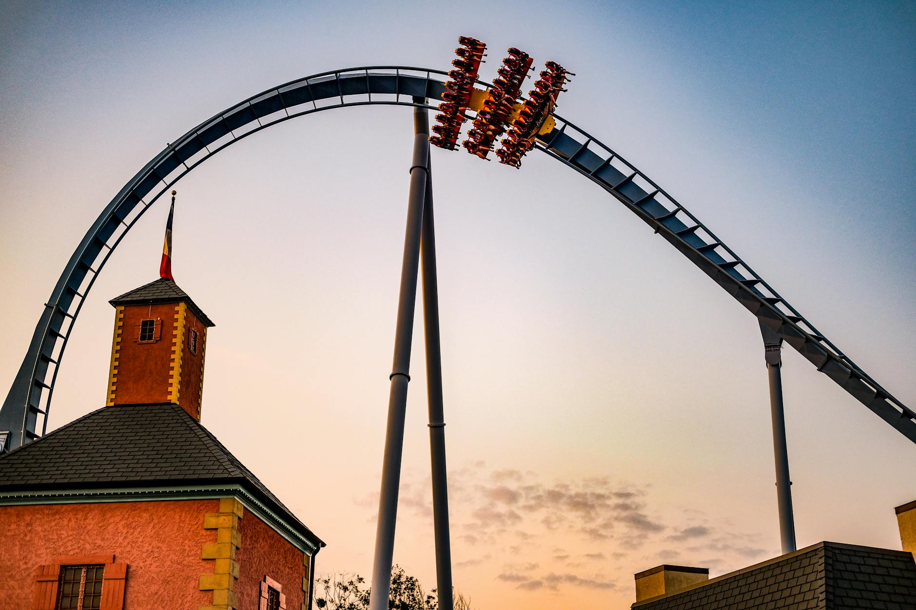 A roller coaster loop silhouetted against a vibrant sunset sky, capturing excitement and adventure.