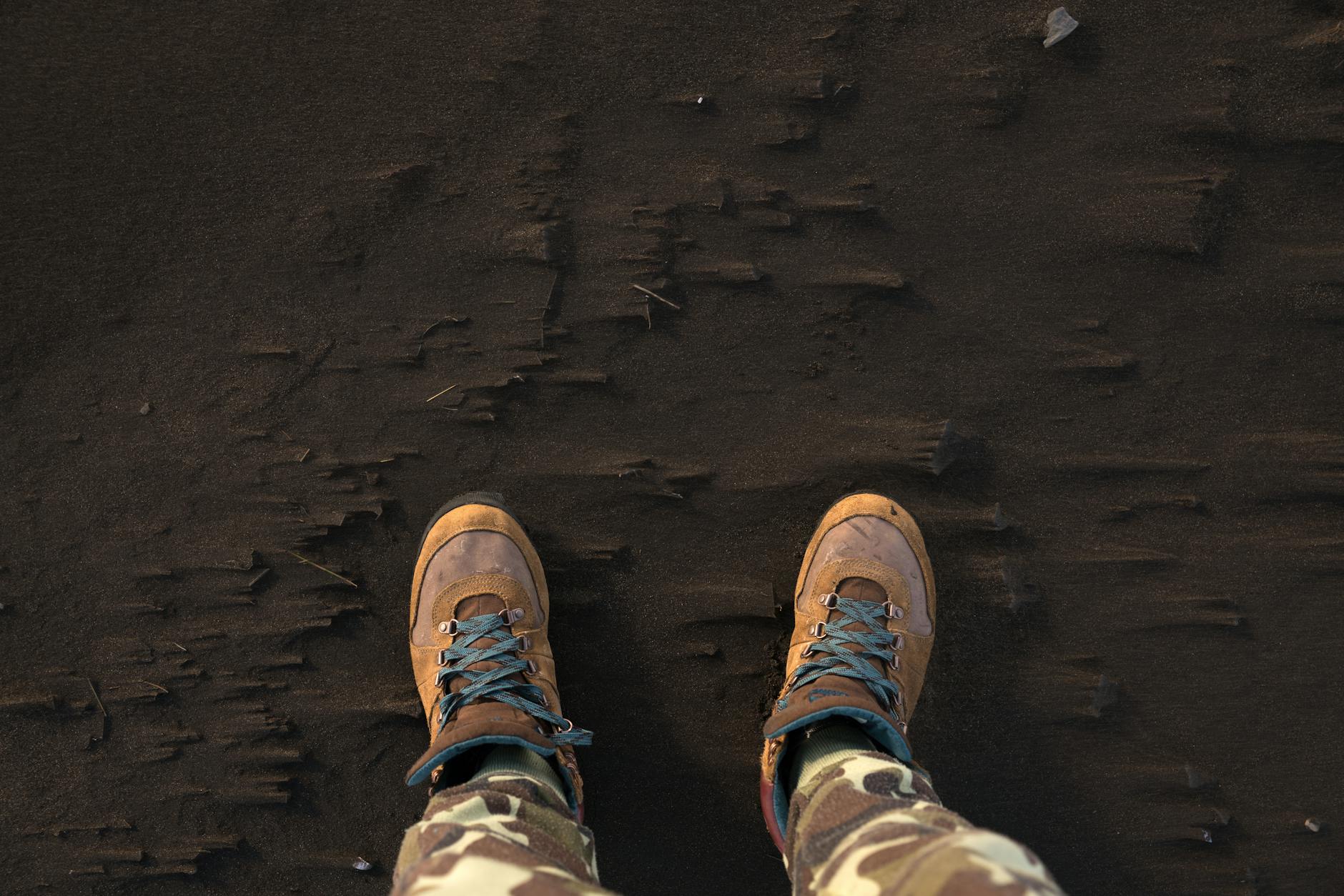 Top view of hiking boots on a sandy surface, ideal for adventure concepts.